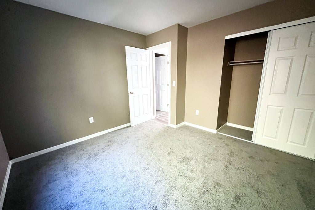 A room with a carpeted floor and two white doors.