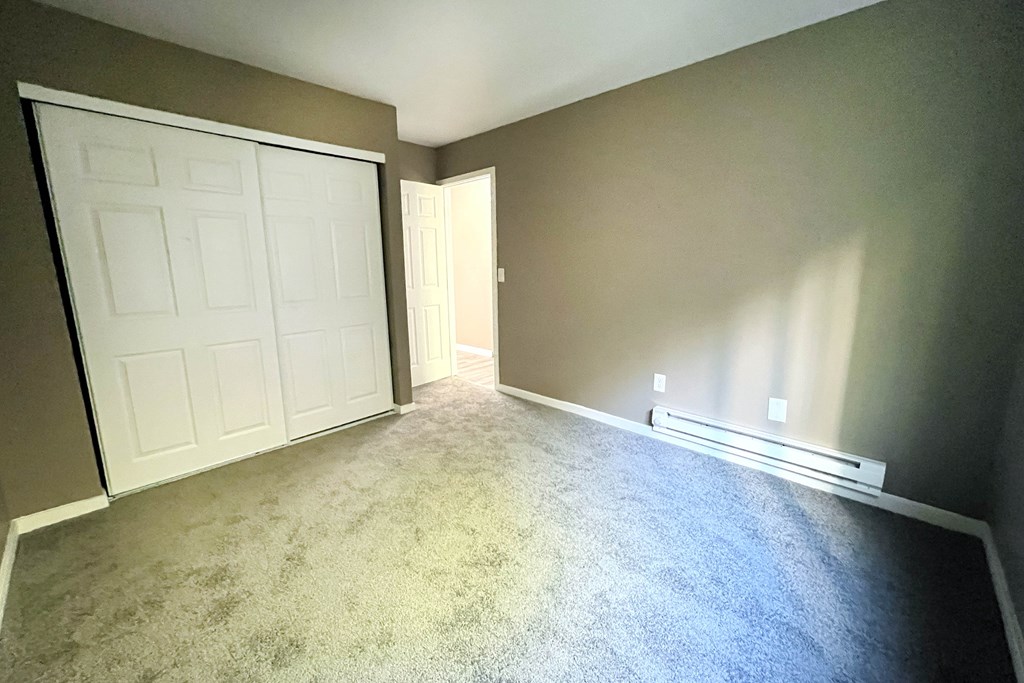 A room with a white door and carpeted floor.