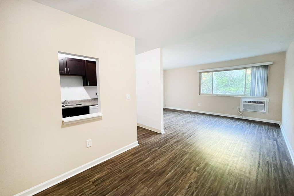 A room with wood flooring and a window with blinds.