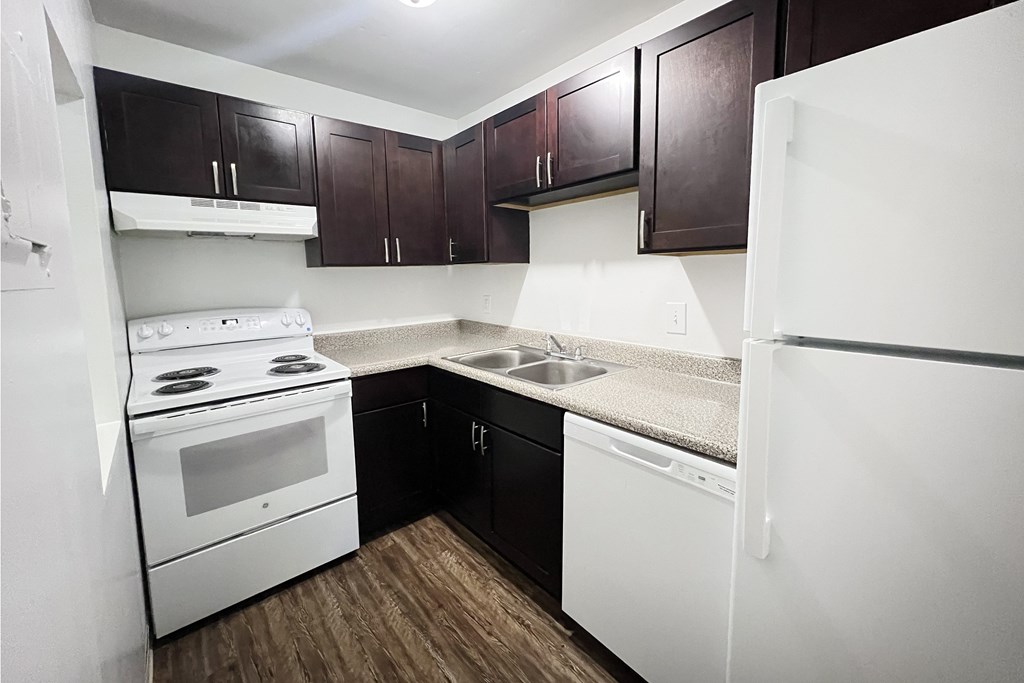 A white stove and refrigerator in a kitchen with dark brown cabinets.