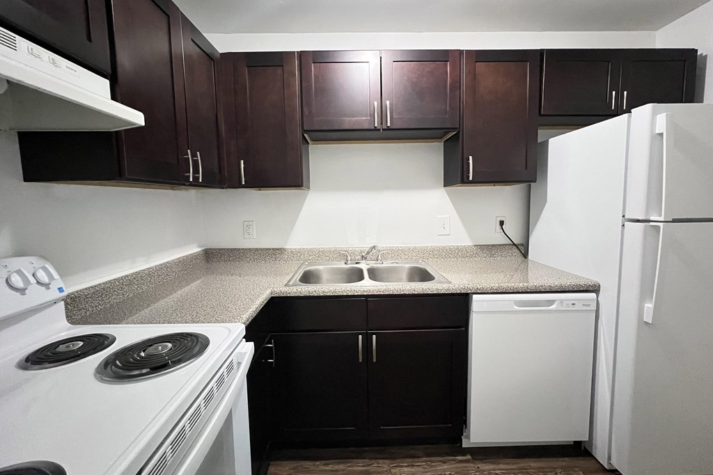 A kitchen with white appliances and dark brown cabinets.
