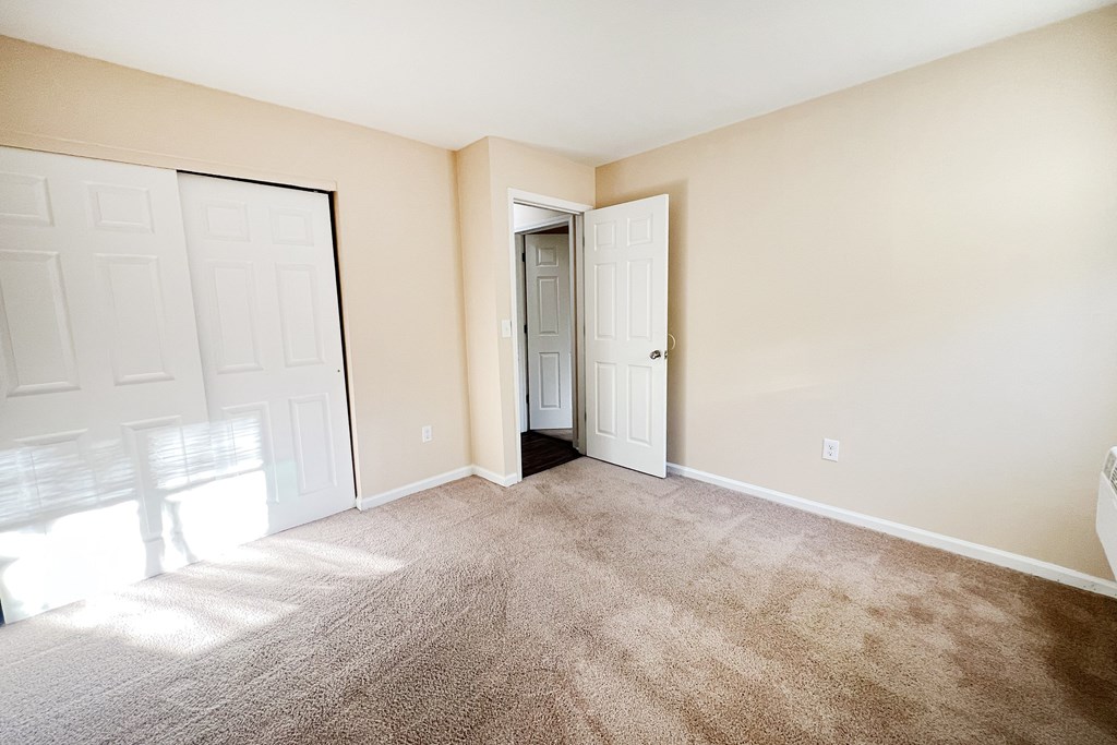 A room with a carpeted floor and two doors, one of which is open.