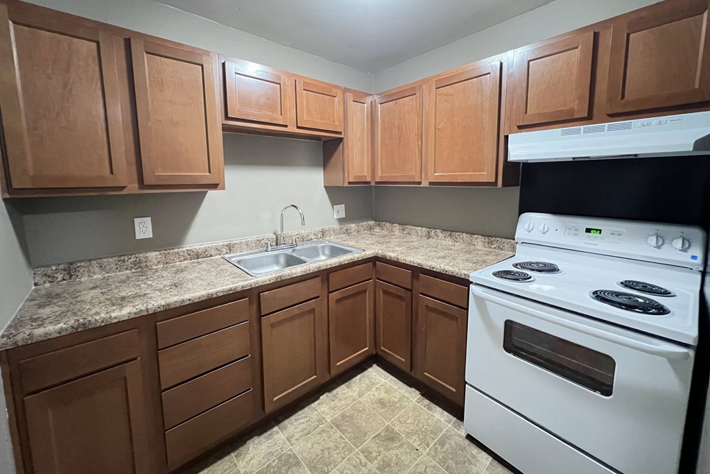 A kitchen with brown cabinets and a white stove.