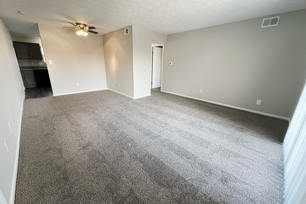 an empty living room with carpet and a ceiling fan at Revere Village Apartments, Centerville, OH, 45458