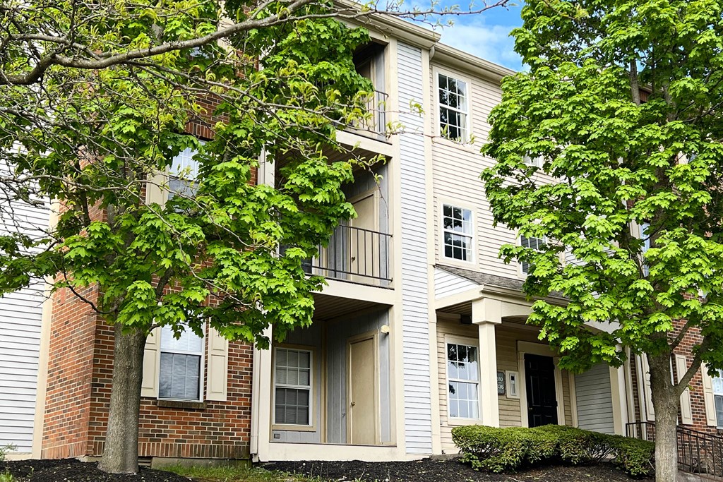 a picture of a three story apartment building with trees in front of it  at Woodhills Apartments, West Carrollton, OH, 45449