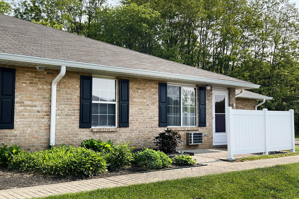 a brick house with black shutters and a white fence  at Wyndemere Apartments, Franklin, 45005
