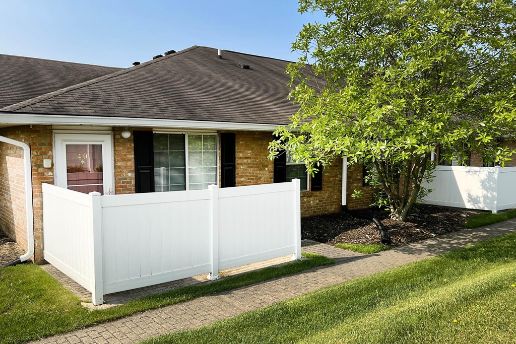 a white privacy fence in front of a brick house  at Wyndemere Apartments, Franklin, Ohio