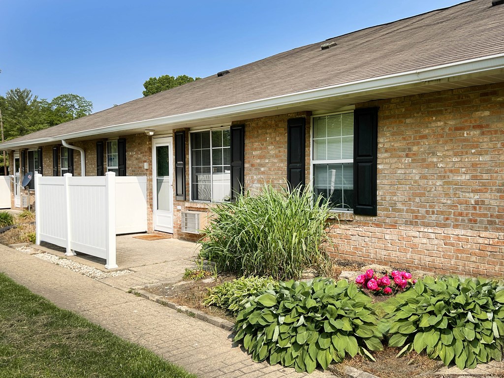 a white fence in front of a brick building  at Wyndemere Apartments, Ohio, 45005