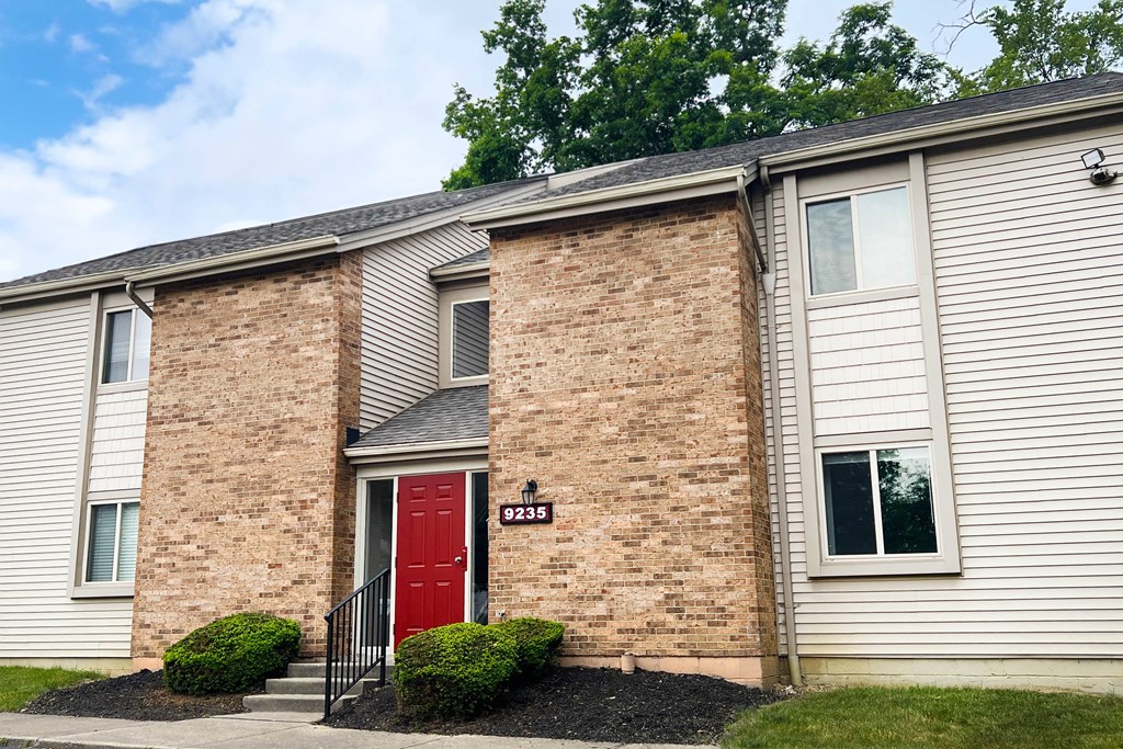 a brick building with a red door and white siding  at Hunter's Creek Apartments, Cincinnati, Ohio