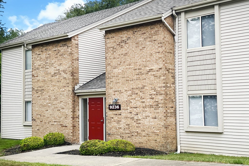 a brick building with a red door and a white siding  at Hunter's Creek Apartments, Cincinnati, 45242