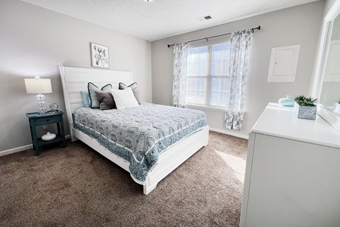 A bedroom with a large bed and a nightstand with a lamp.