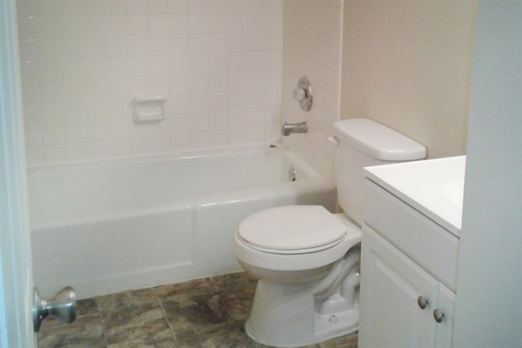 A white toilet sits next to a white cabinet in a bathroom.