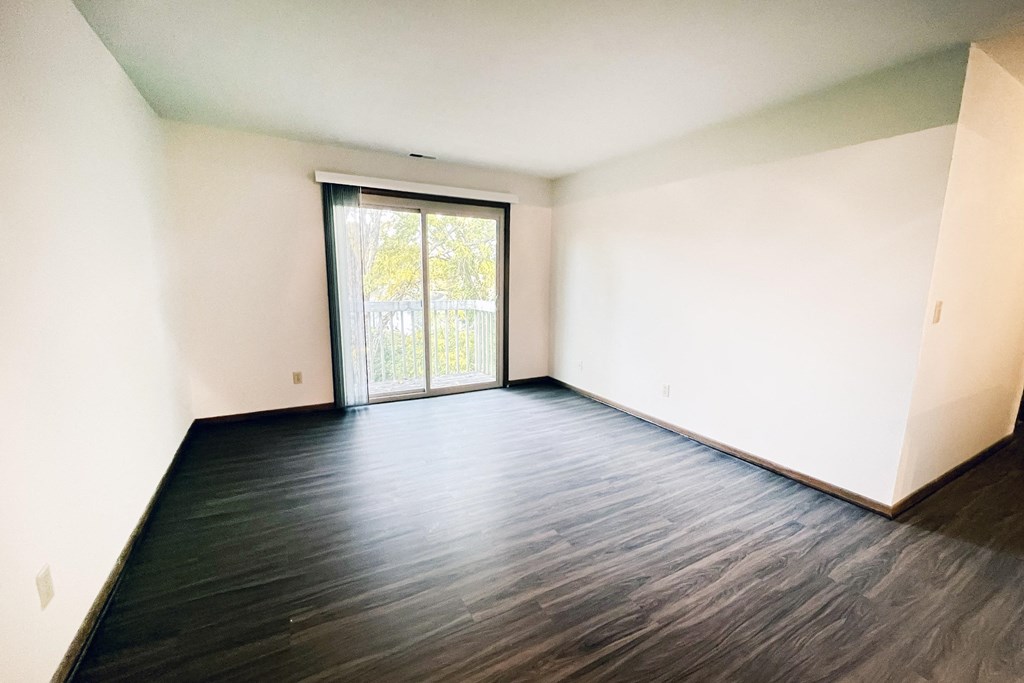an empty living room with wood floors and a sliding glass door at Forest Creek Apartments, Ohio 45044