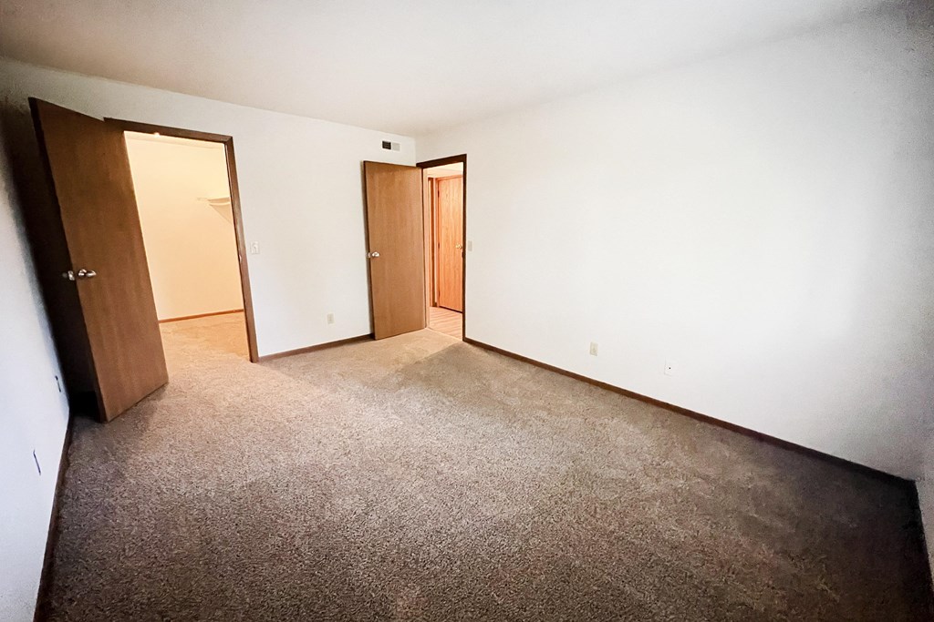an empty room with a carpeted floor and two doors at Forest Creek Apartments, Middletown, OH