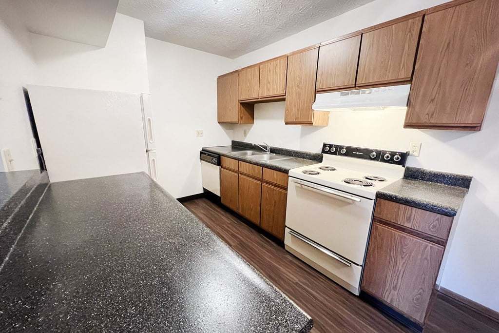 an empty kitchen with white appliances and wooden cabinets at Forest Creek Apartments, Middletown, OH 45044