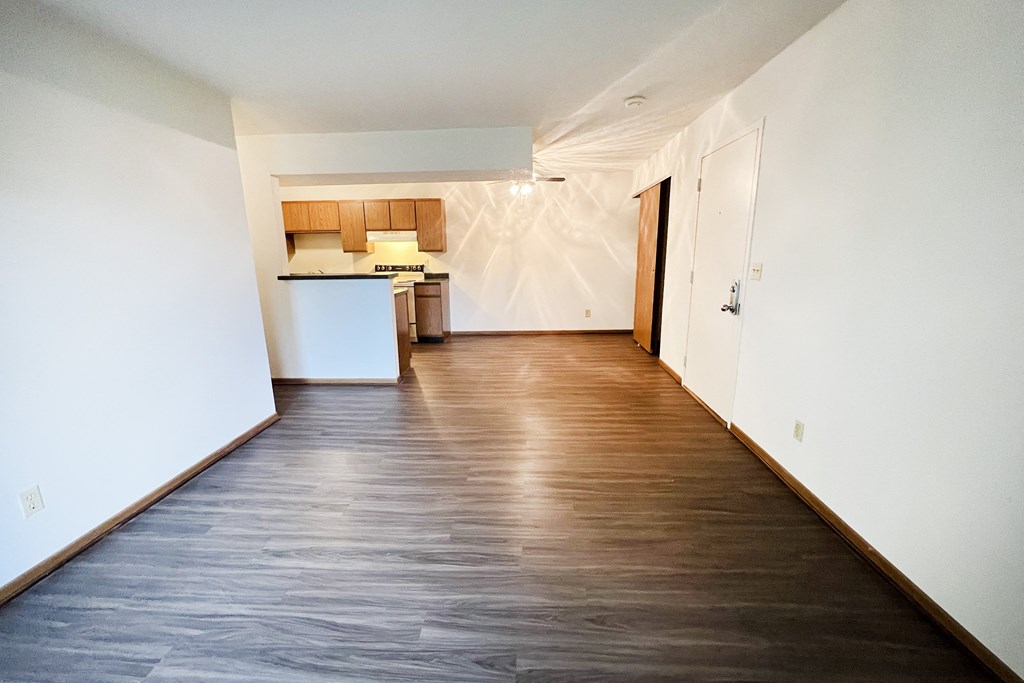 an empty living room with wood flooring and a kitchen at Forest Creek Apartments, Middletown, Ohio