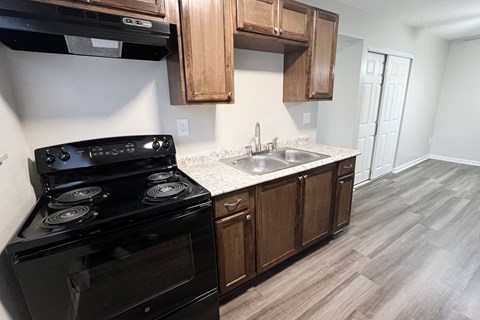 an empty kitchen with black appliances and wooden cabinets at Crown Court Apartments, Florence, KY, 41042