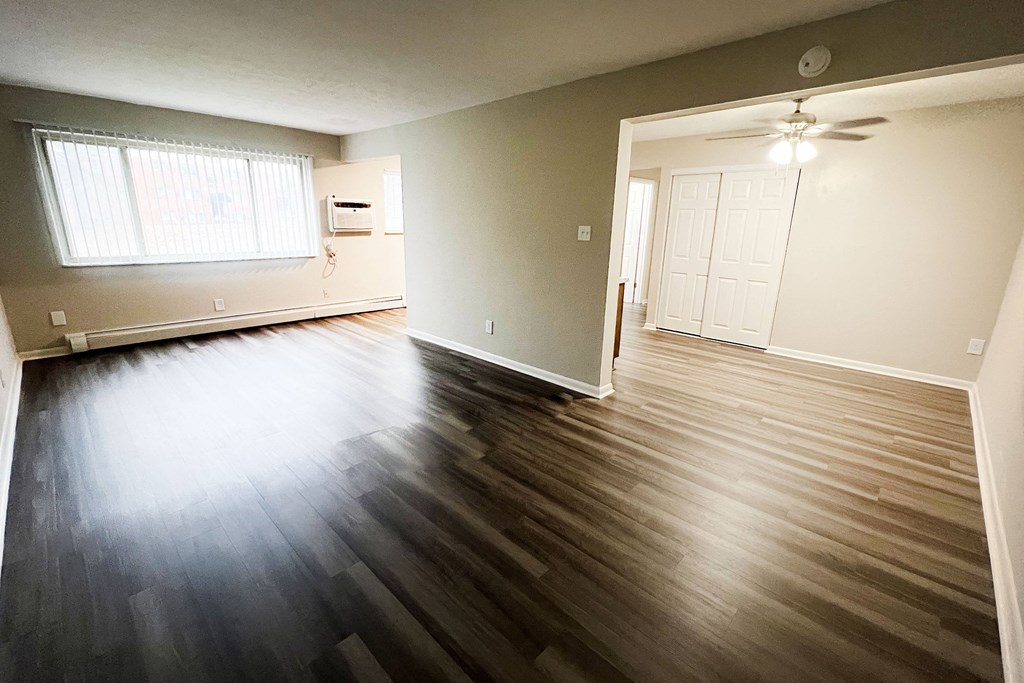 an empty living room with hard wood floors and a window at Crown Court Apartments, Florence, KY, 41042
