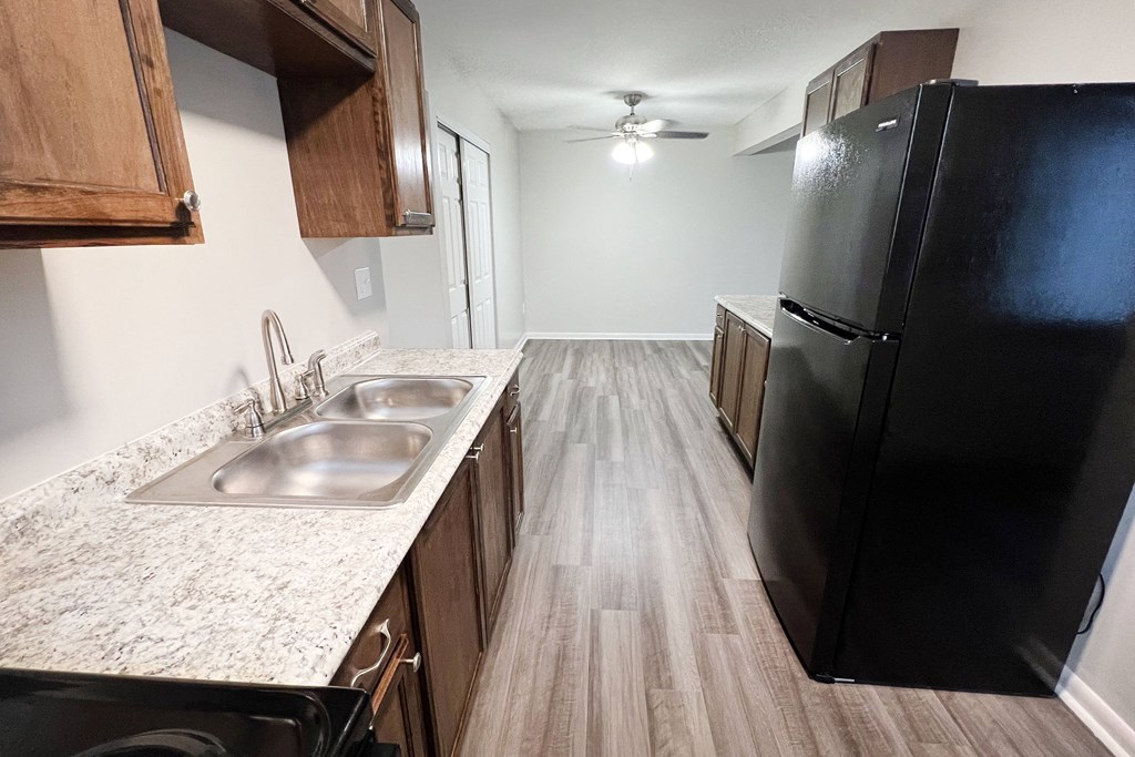 an empty kitchen with a black refrigerator and a sink at Crown Court Apartments, Florence, Kentucky