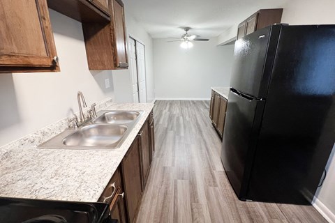 an empty kitchen with a black refrigerator and a sink at Crown Court Apartments, Florence, Kentucky