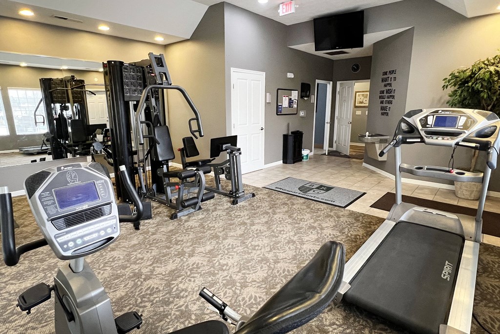 a gym with exercise equipment and a tv on the wall