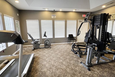 a gym with treadmills and other exercise equipment in a room with windows