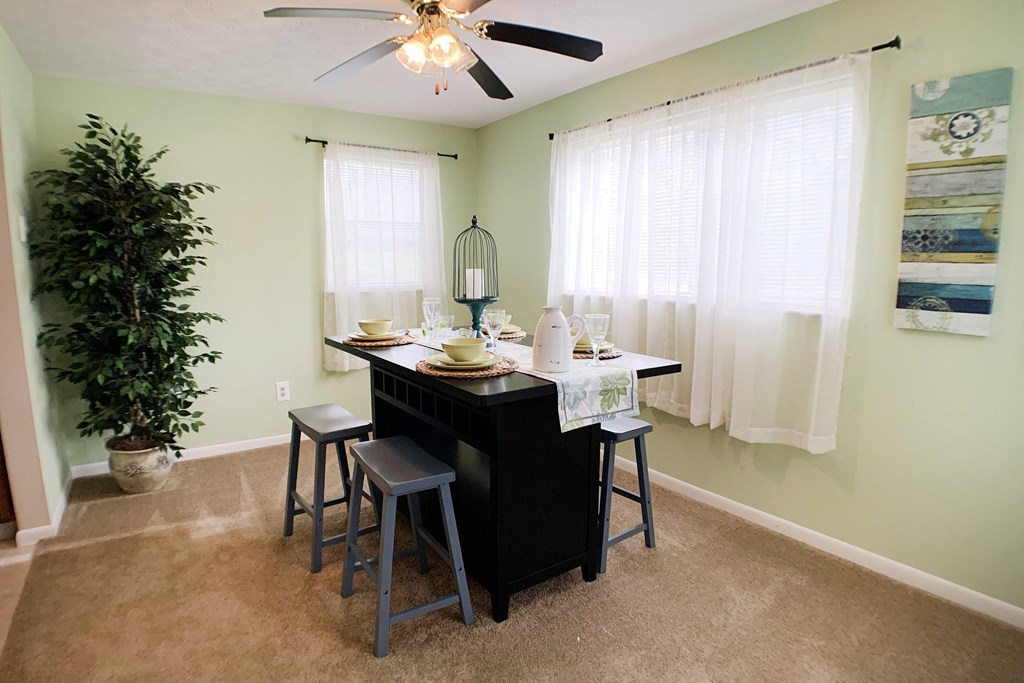 an island with stools in a dining room with a ceiling fan at The Vinings Apartments, Cincinnati, OH