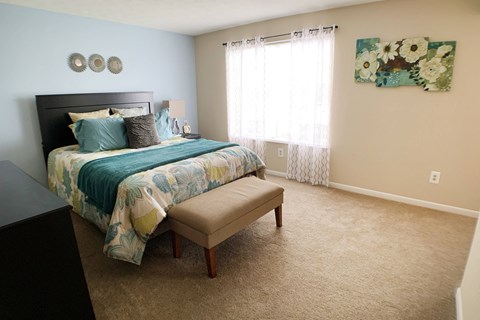 a bedroom with a bed and a chair and a window at The Vinings Apartments, Cincinnati