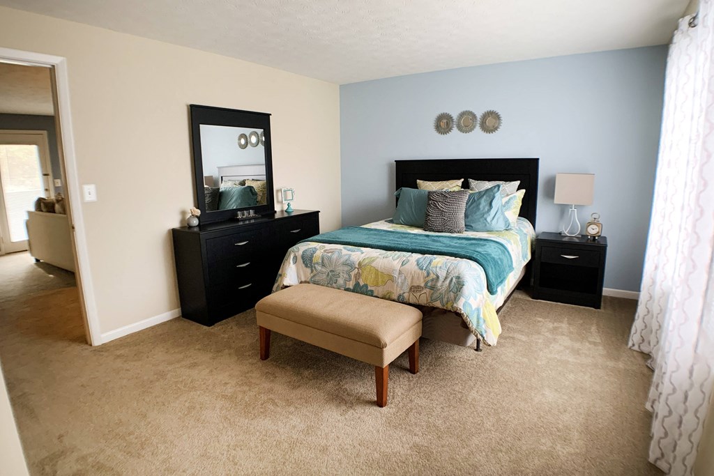 a bedroom with a bed and a dresser and a window at The Vinings Apartments, Cincinnati, 45245