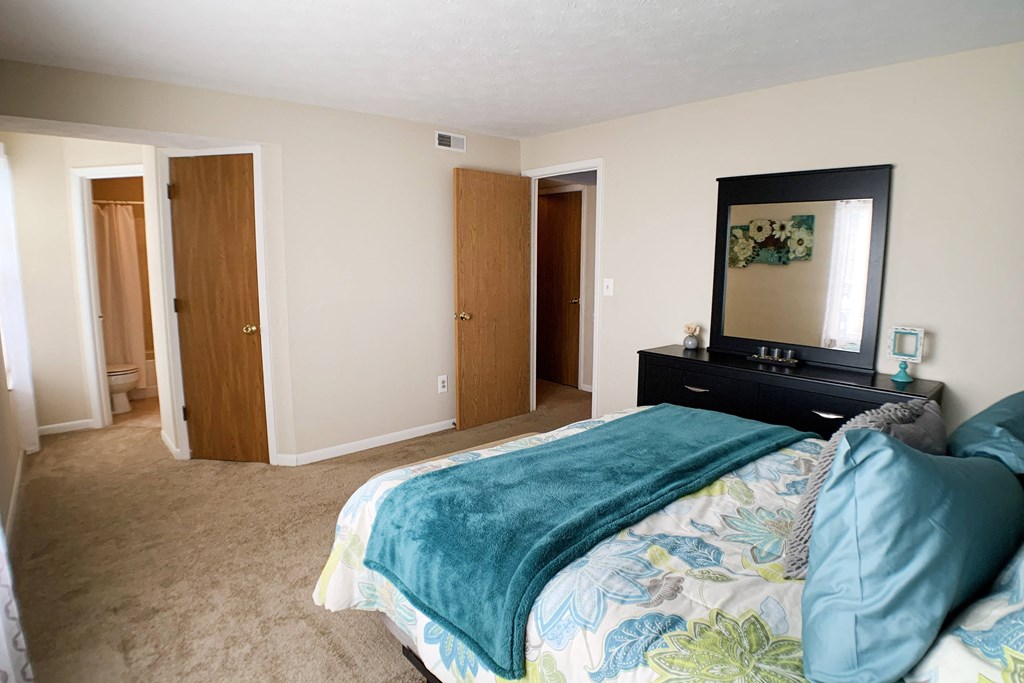 a bedroom with a bed and a mirror on the wall at The Vinings Apartments, Cincinnati, Ohio