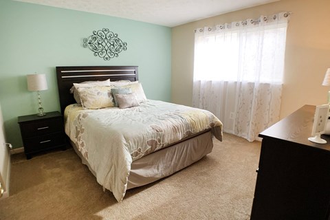 a bedroom with a bed and a dresser and a window at The Vinings Apartments, Cincinnati, OH, 45245