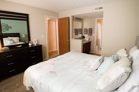 a bedroom with a large white bed and a mirror at The Vinings Apartments, Cincinnati