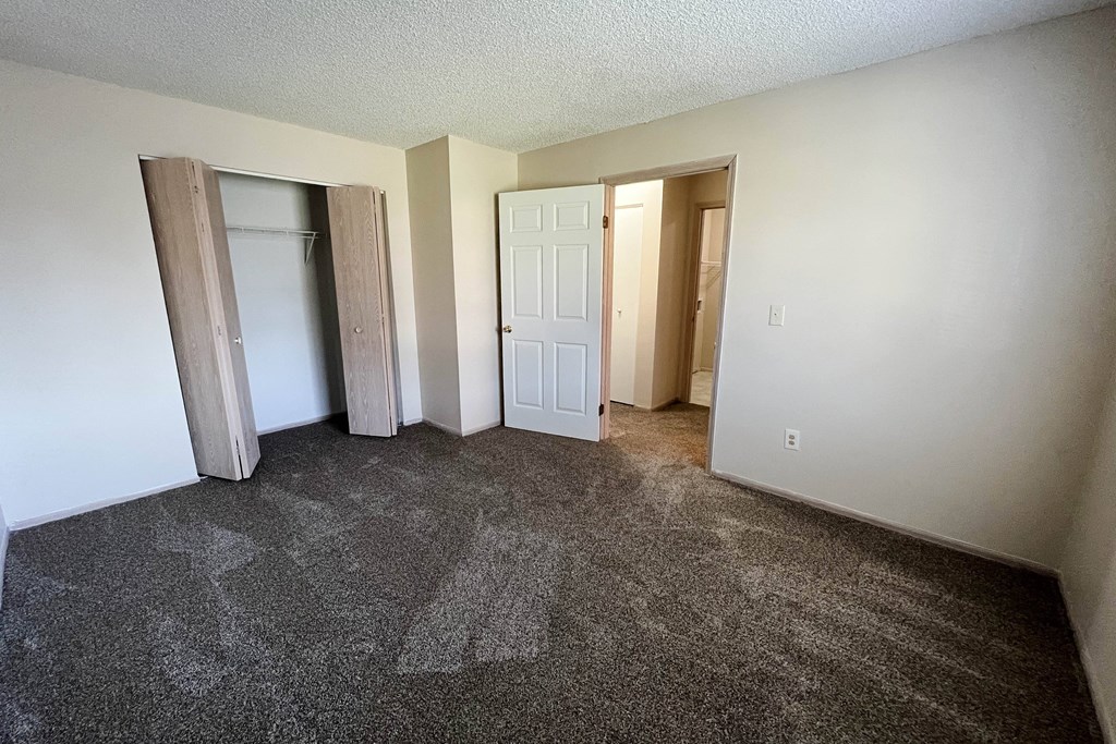 an empty living room with carpet and a door to a closet at Eagle Crest Apartments, Ohio, 43119