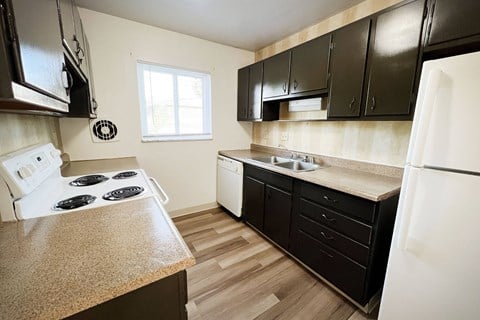 the view of a kitchen with black cabinets and white appliances