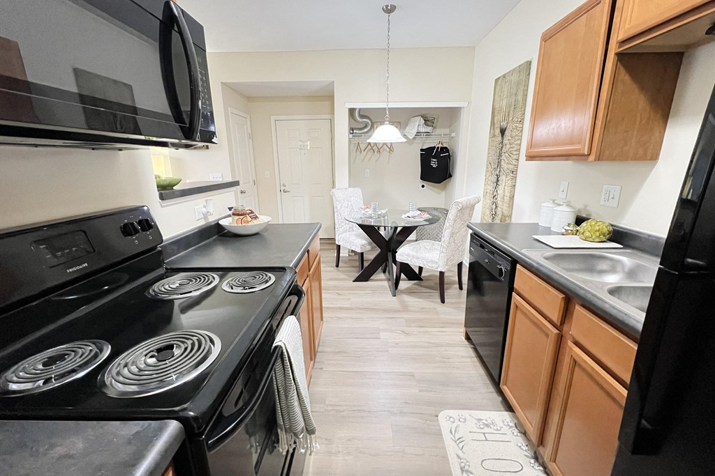a kitchen and dining room with black appliances and wooden cabinets at Residences at Northgate Crossing, Ohio, 43235