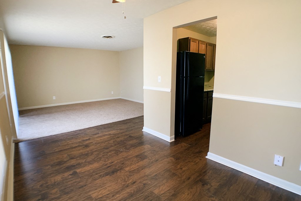 an empty living room with wood floors and a black refrigerator  at Timber Ridge Apartments, Cincinnati