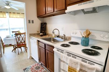 A kitchen with a white stove top oven and a white sink.