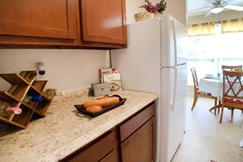 A kitchen with a white refrigerator and wooden cabinets.