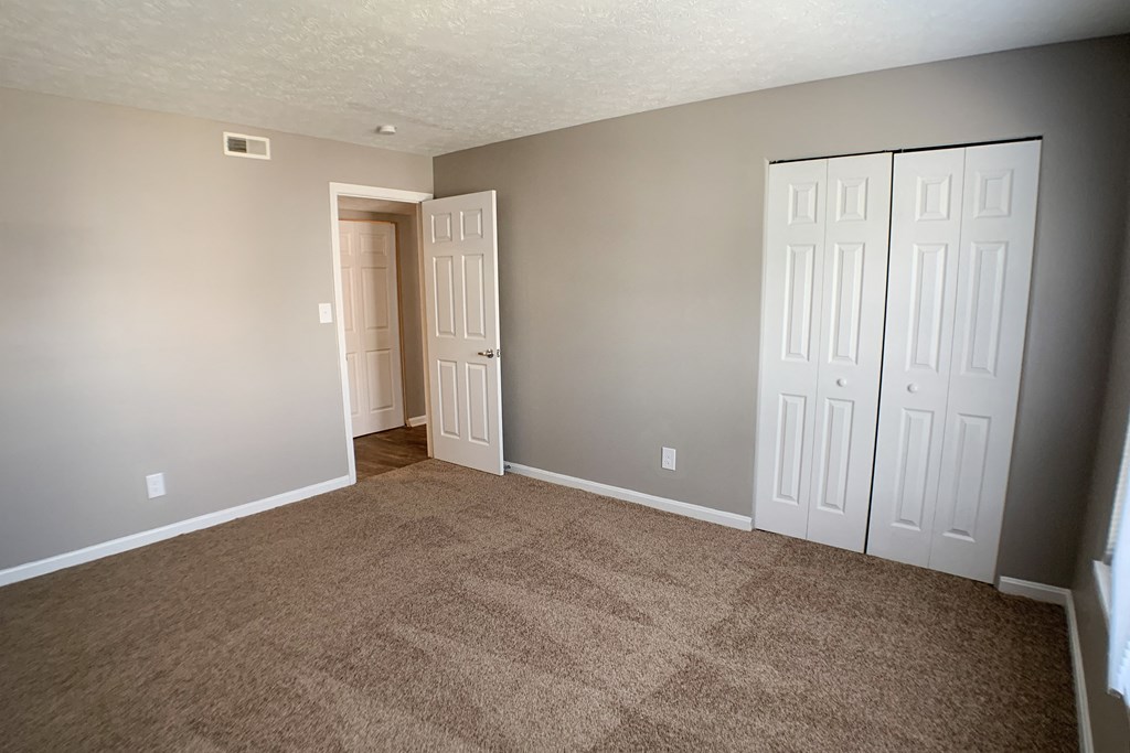an empty living room with carpet and two doors  at Knobs Pointe Apartments, Indiana