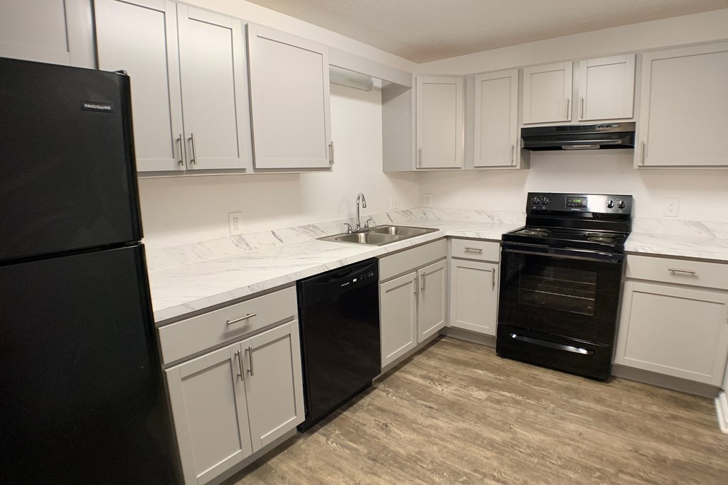 a kitchen with white cabinets and black appliances  at Knobs Pointe Apartments, New Albany