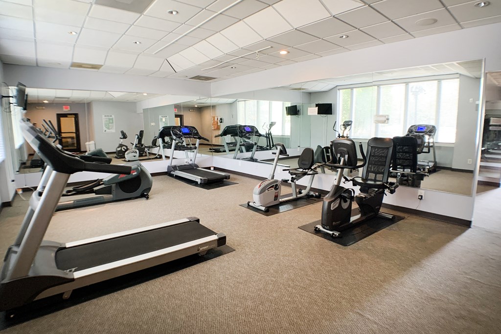 a gym with cardio machines and weights in a large room with windows  at Knobs Pointe Apartments, Indiana