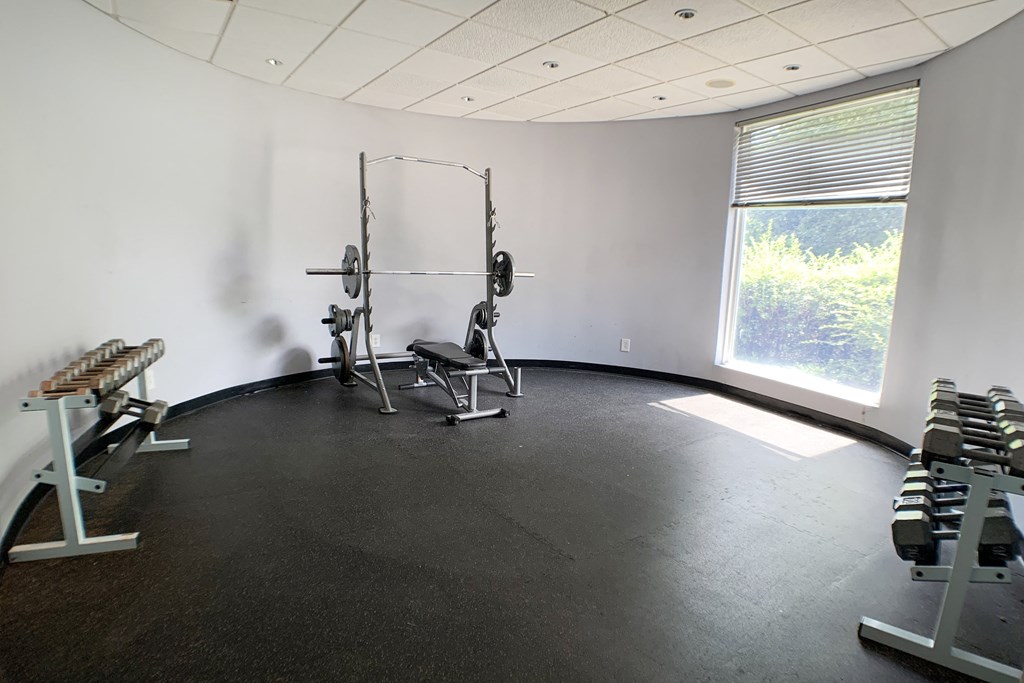 a gym with weights and a window in the corner of a room  at Knobs Pointe Apartments, New Albany, IN