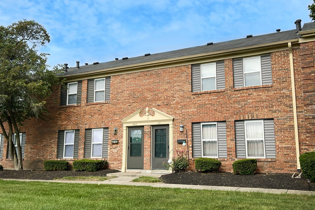 a brick building with a green door and grass at Revere Village Apartments, Centerville, Ohio