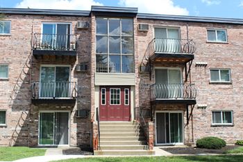 a red brick apartment building with stairs and a red door