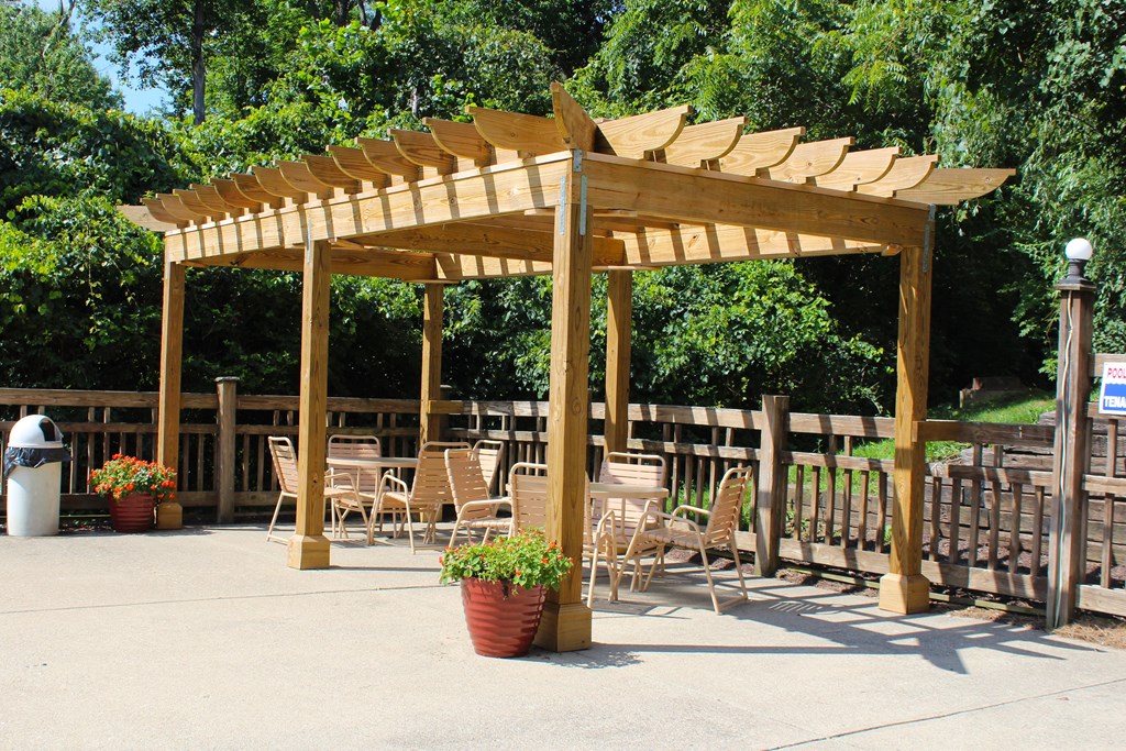 a wooden pergola with tables and chairs under it at The Vinings Apartments, Cincinnati