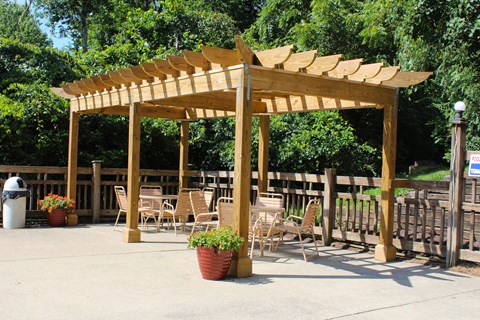 a wooden pergola with tables and chairs under it at The Vinings Apartments, Cincinnati
