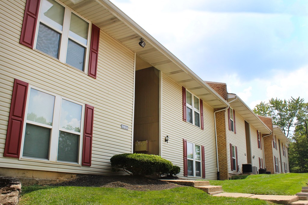 a yellow house with red window shutters and a green yard  at Timber Ridge Apartments, Cincinnati