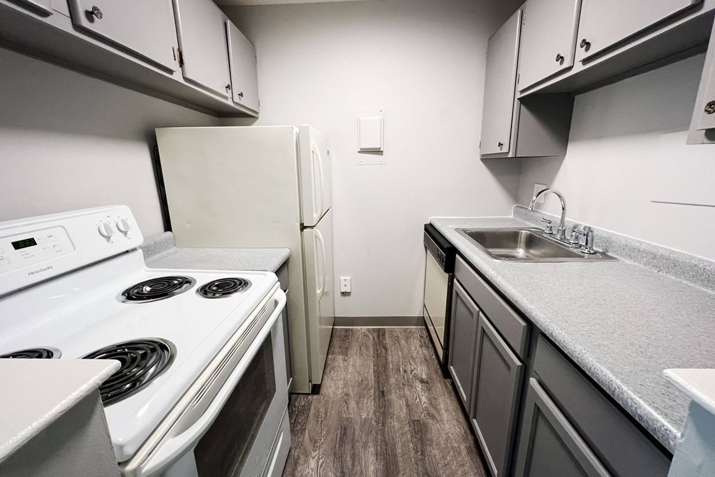 a kitchen with white appliances and gray cabinets  at Summit East - A Senior Community, Cincinnati, Ohio