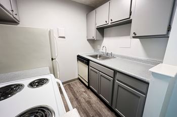 A small kitchen with a white fridge and a white sink.