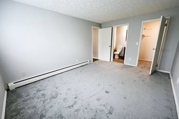 A room with a carpeted floor and three open doors.